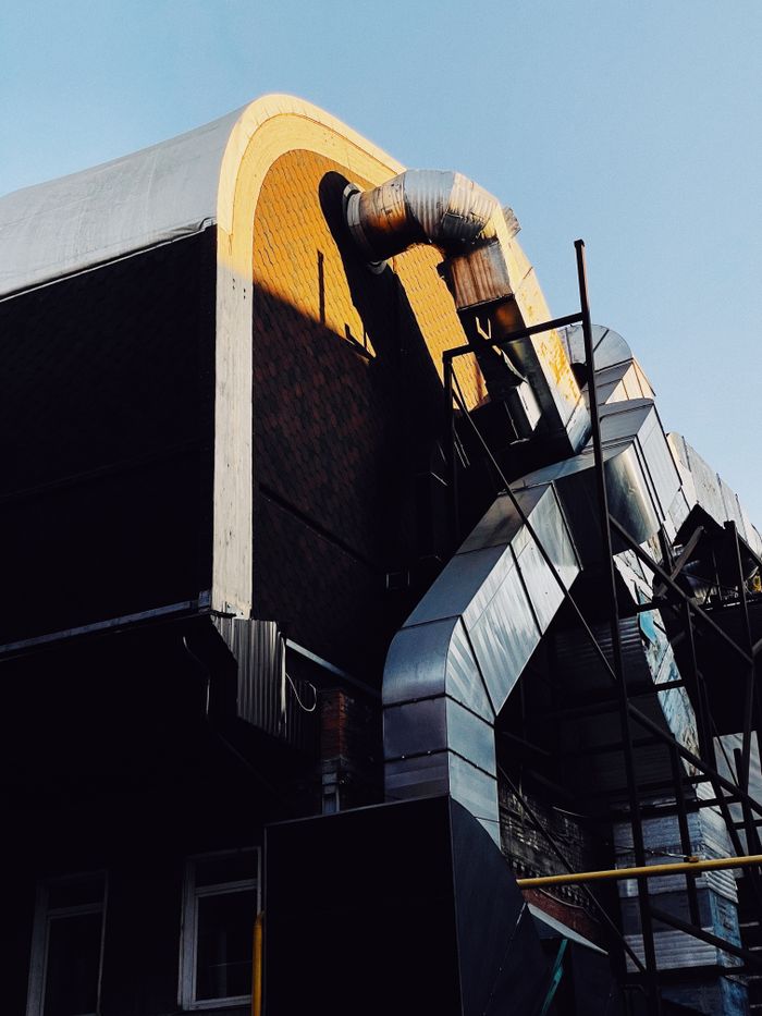 A modern industrial building exterior showcasing sleek ductwork and clear skies.